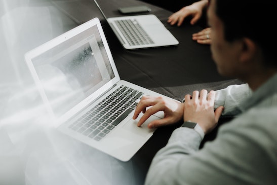 Mann arbeitet mit Händen am Laptop